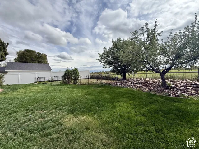 Expansive green lawn with mature trees and a rock-lined border