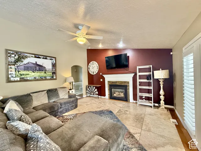 Living space featuring a built-in fireplace with a white mantel, ceiling fan, and tile flooring