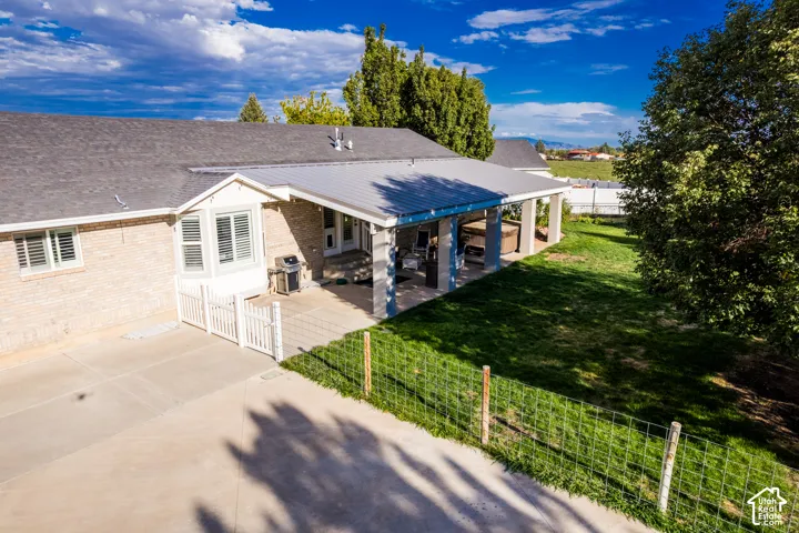 Expansive concrete patio with a covered outdoor living area, featuring a metal roof and support columns