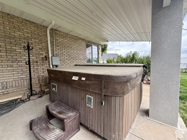 Covered patio with brick siding and a built-in spa