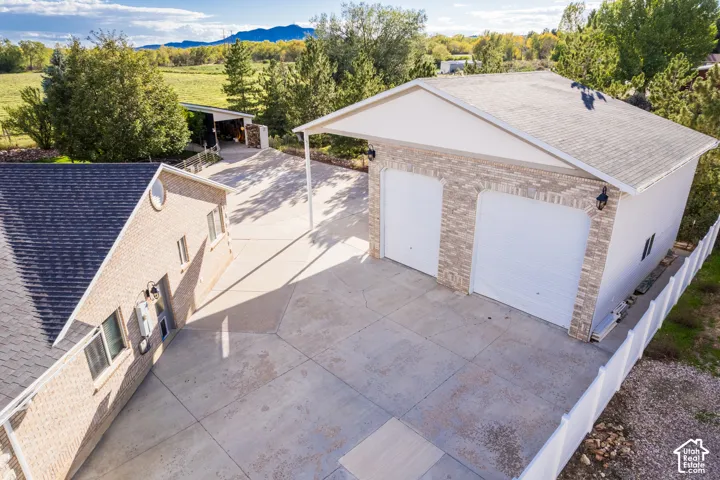 Detached two-car garage with brick veneer, concrete driveway, and white picket fencing