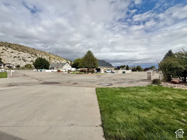 Expansive undeveloped lot with existing concrete paving and mature landscaping elements, bordered by established residential properties