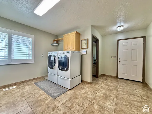 Large format tile flooring, window with plantation shutters, built-in cabinetry, and overhead lighting