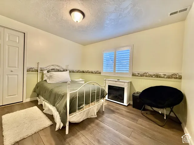 Wood-finish flooring, white bi-fold closet doors, built-in window shutters, and a decorative electric fireplace