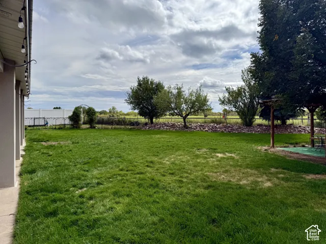 Expansive green lawn with mature trees and a rock-lined garden bed