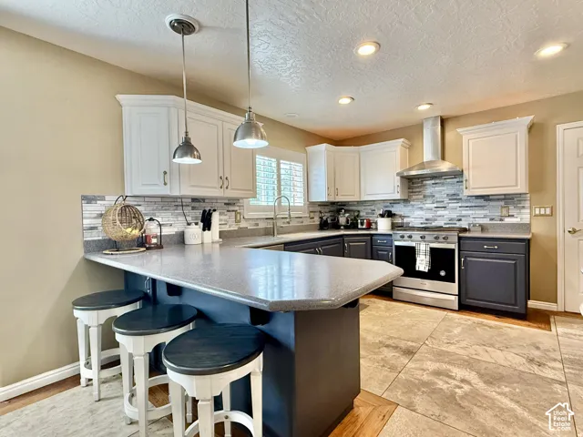 Two-tone cabinetry with an expansive island, stainless steel appliances, and a tiled backsplash, all complemented by large format floor tiles