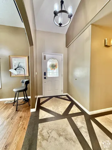 Front entry with vaulted ceiling and a decorative chandelier