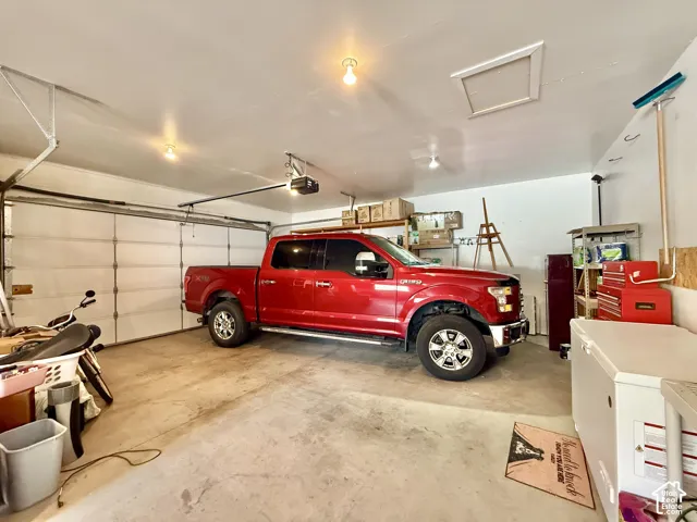 Attached garage with a sectional garage door, concrete flooring, and ceiling-mounted light fixtures