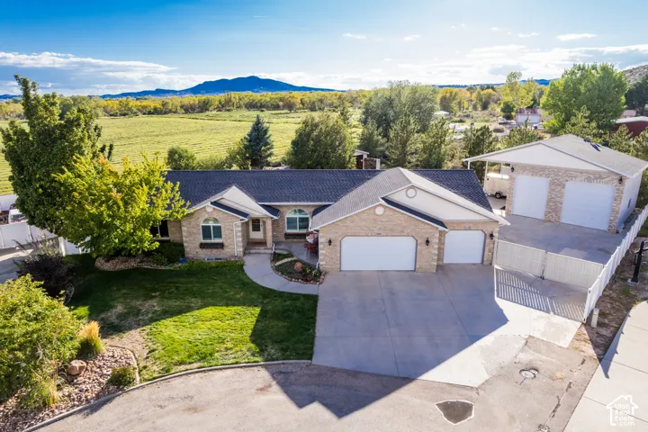 Brick exterior residence featuring a two-car attached garage, paved driveway, mature landscaping, and a separate two-car detached garage