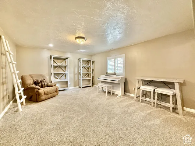 Expansive room with neutral carpeting, recessed lighting, and a window with plantation shutters