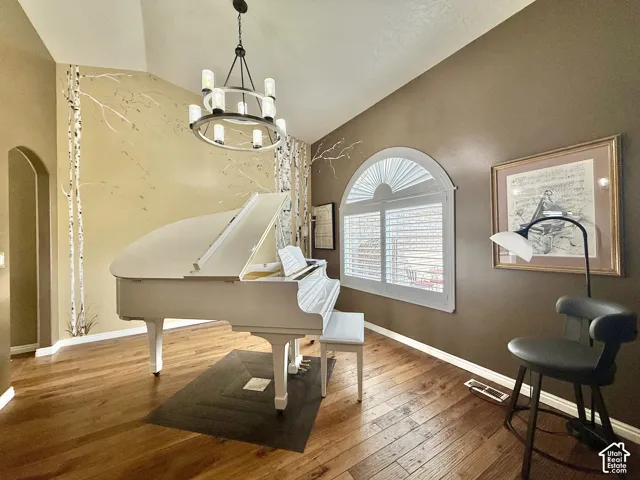 Hardwood flooring, vaulted ceiling, arched doorway, arched window, and a contemporary chandelier