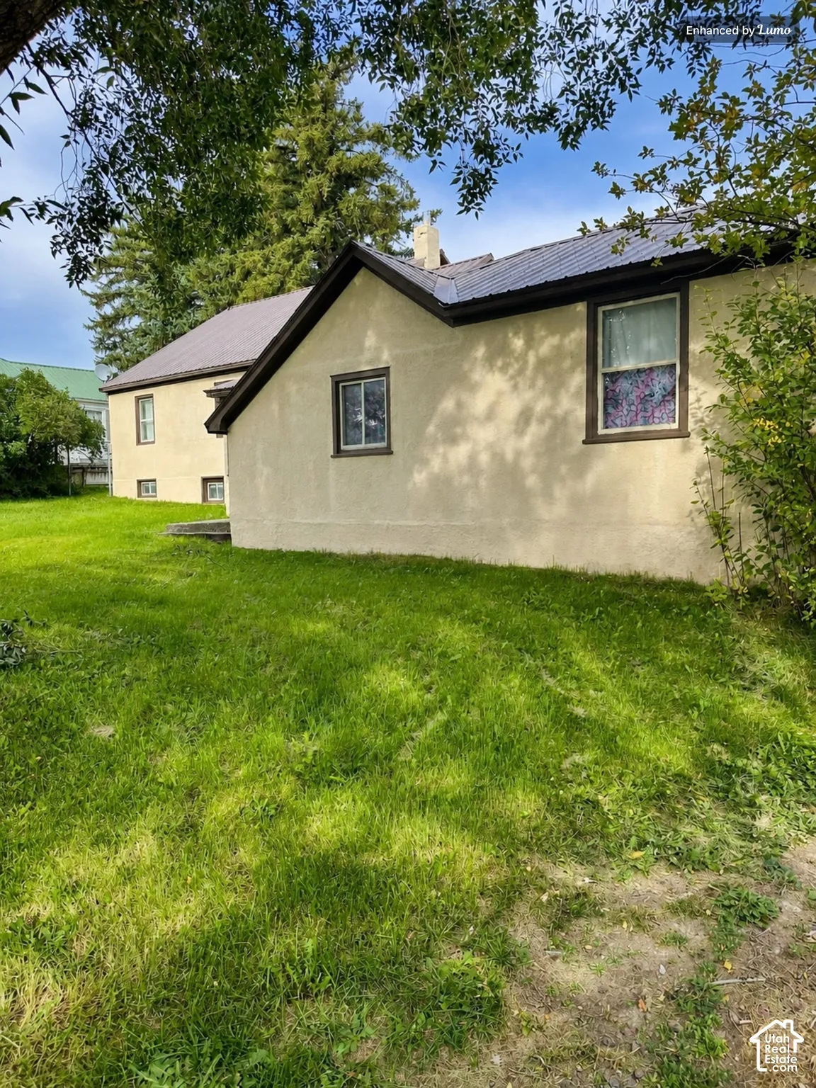 Stucco exterior with contrasting window trim, gabled roofline, and ample green space