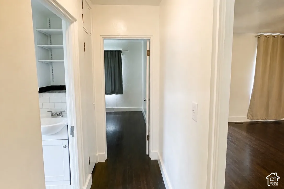 Hardwood flooring, white painted walls, built-in shelving, white subway tile, and a white vanity with a vessel sink