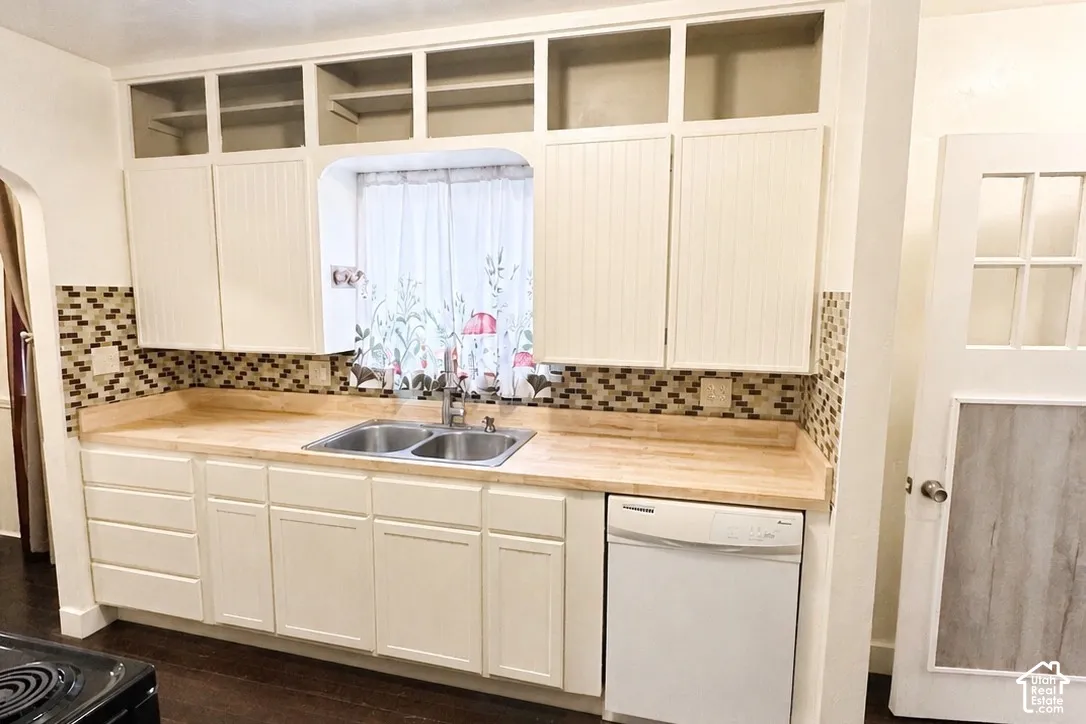Kitchen featuring white cabinetry, wood-finish countertops, mosaic tile backsplash, double basin stainless steel sink, and a built-in dishwasher