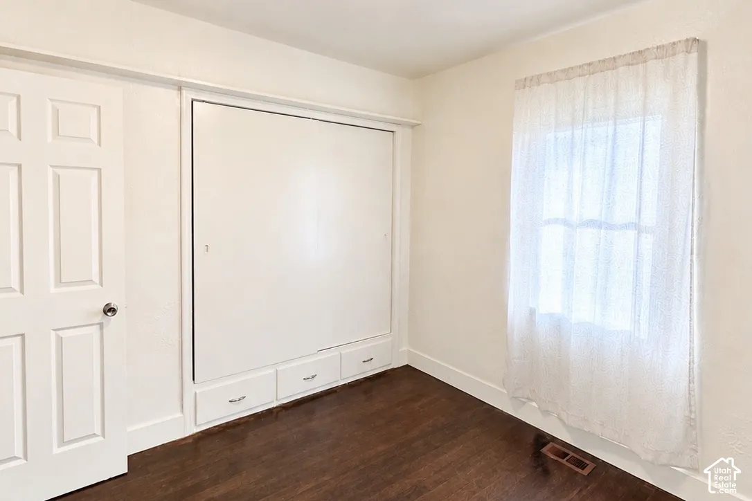 Built-in wall unit with integrated storage drawers, wood-finish flooring, and a multi-pane window