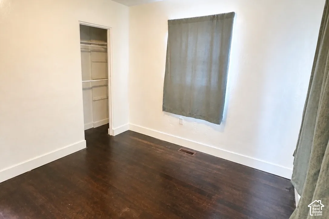 Rich wood-finish flooring, white painted walls, and an integrated closet with shelving