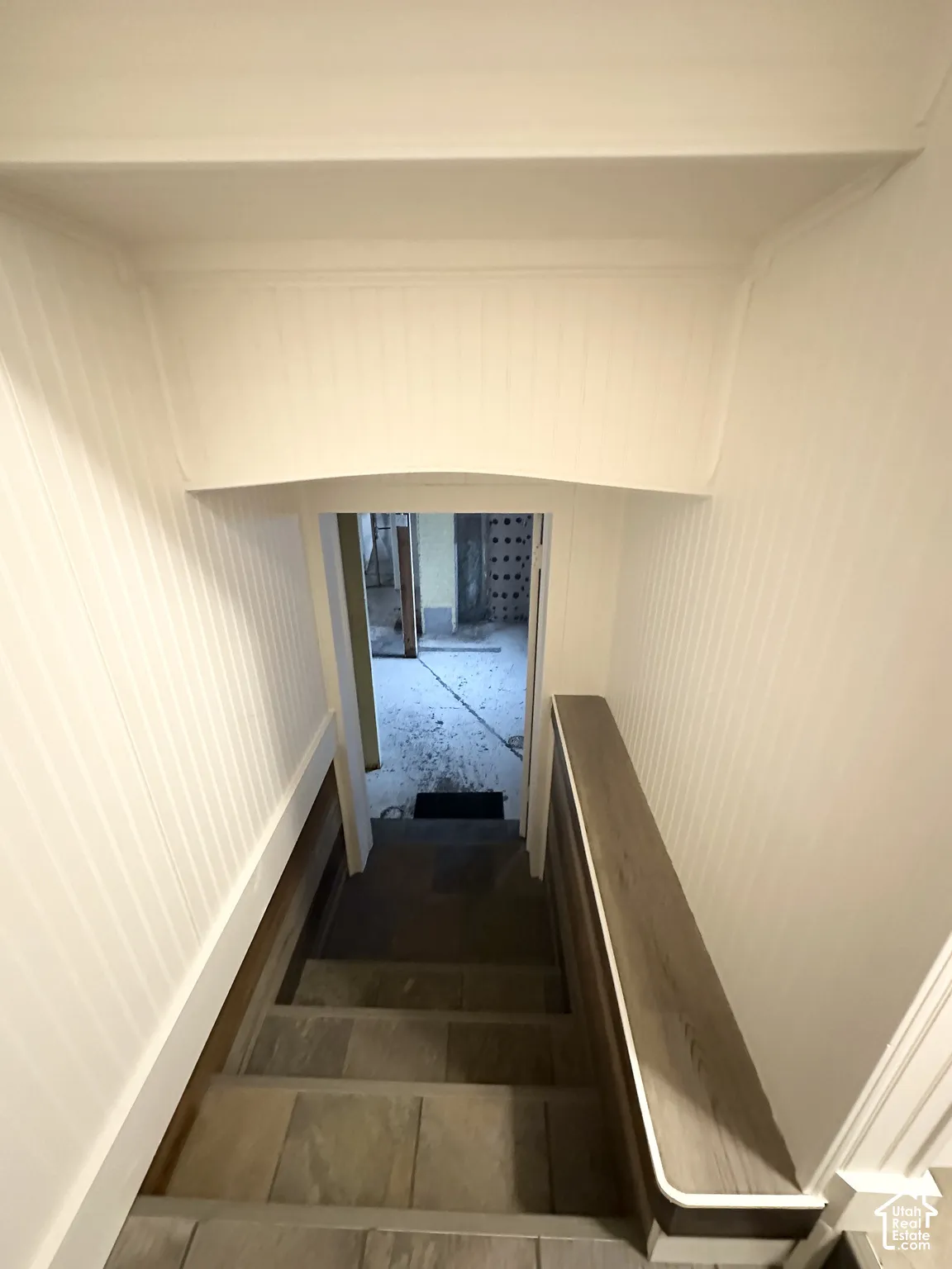Stairway featuring board and batten wall paneling, a wood-finish handrail, and tiled treads