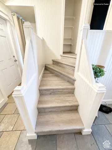 Curved staircase featuring wood-finish treads and white beadboard paneling