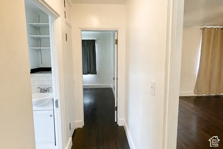 Hardwood flooring, white painted walls, built-in shelving, white subway tile, and a white vanity with a vessel sink