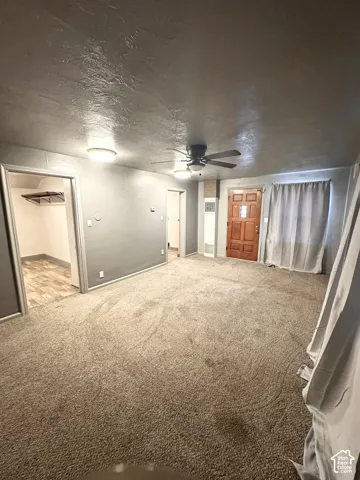 Carpeted living area with overhead lighting and a ceiling fan