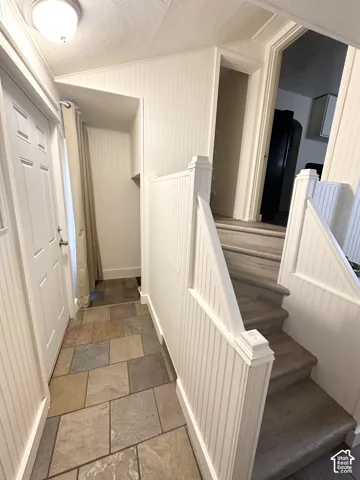 Multi-toned tile flooring, beadboard wall paneling, white trim, and a staircase with carpeted treads