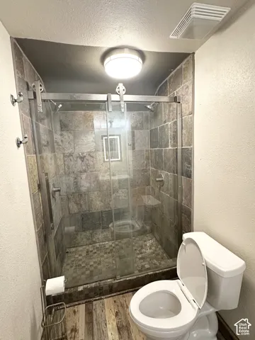 Glass-enclosed shower with stone tile surround and mosaic tile flooring