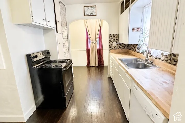 Kitchen featuring wood-finish flooring, white cabinetry, a dual basin sink, and a mosaic tile backsplash, breakfast nook