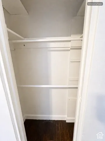 Built-in closet shelving and hanging rods with dark wood-finish flooring