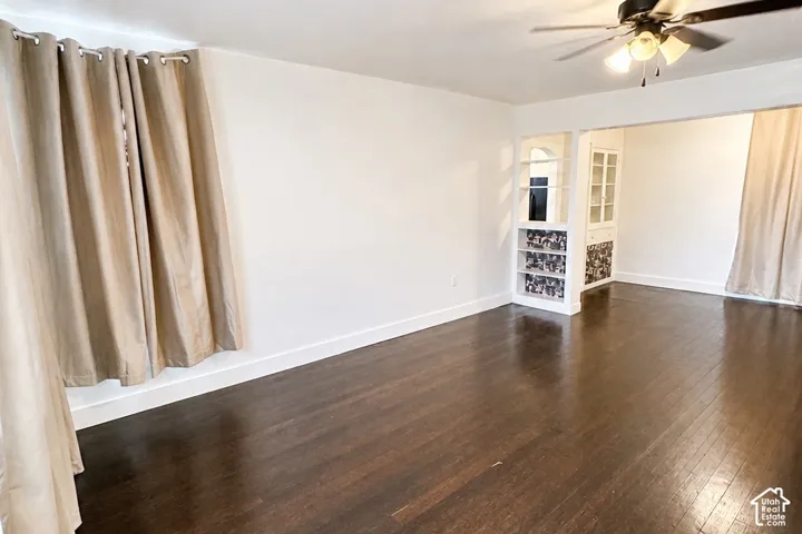 Dark wood-finish flooring, white walls, built-in shelving, and a ceiling fan