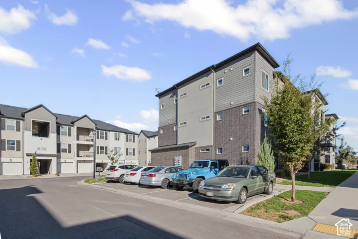Multi-story building featuring a blend of brick and horizontal siding, individual garage access, and a dedicated parking area