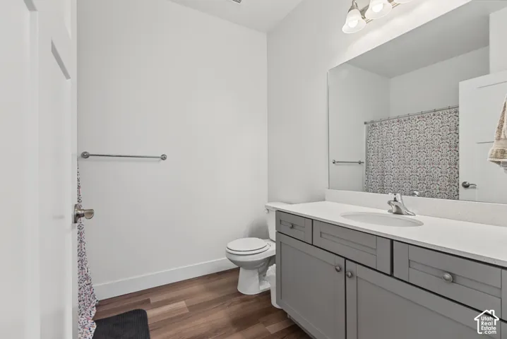 Bathroom featuring a vanity with a white countertop and gray cabinetry, wood-finish flooring, and a wall-mounted mirror
