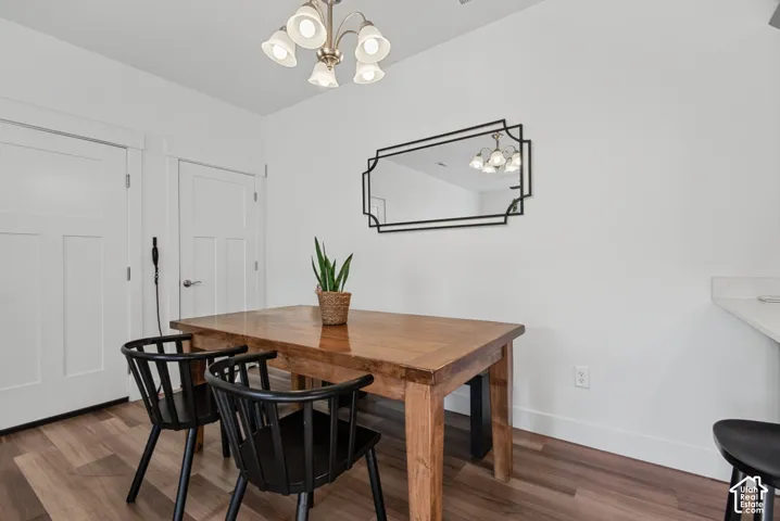 Wood-finish flooring with white baseboards, light-colored walls, and a five-light chandelier