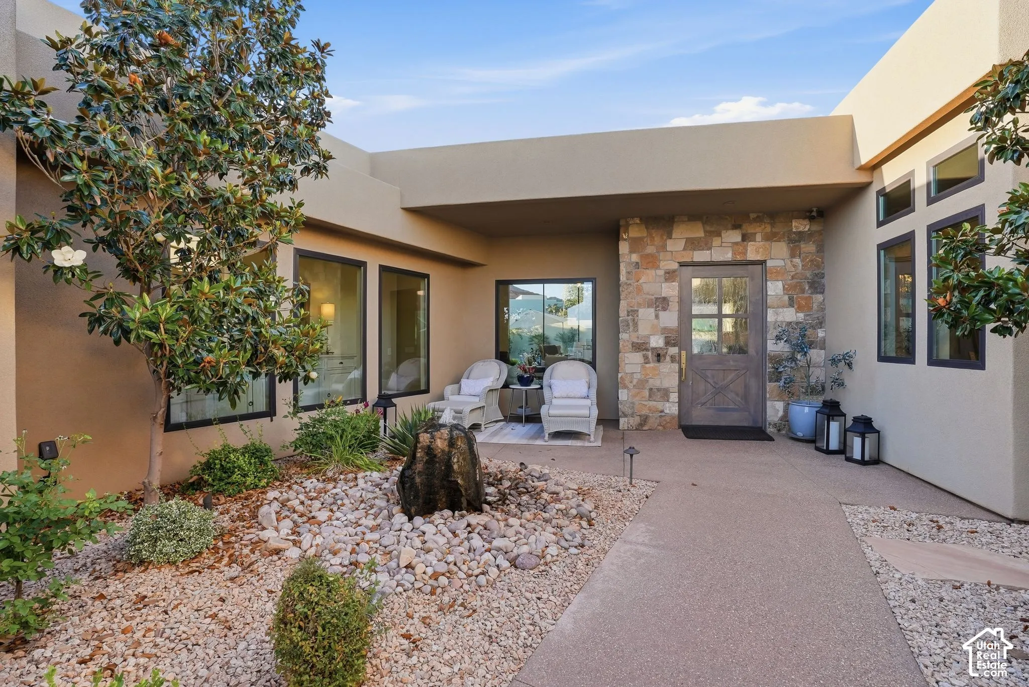 Stucco exterior with stone accent wall, wood-finish entry door, and multi-pane windows