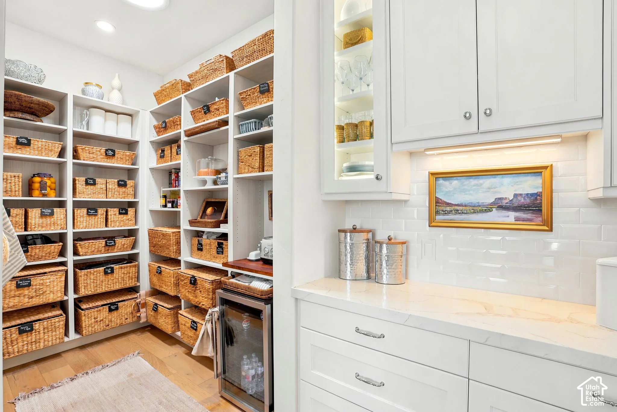 Walk-in pantry with extensive built-in shelving, wood-finish flooring, and a beverage cooler