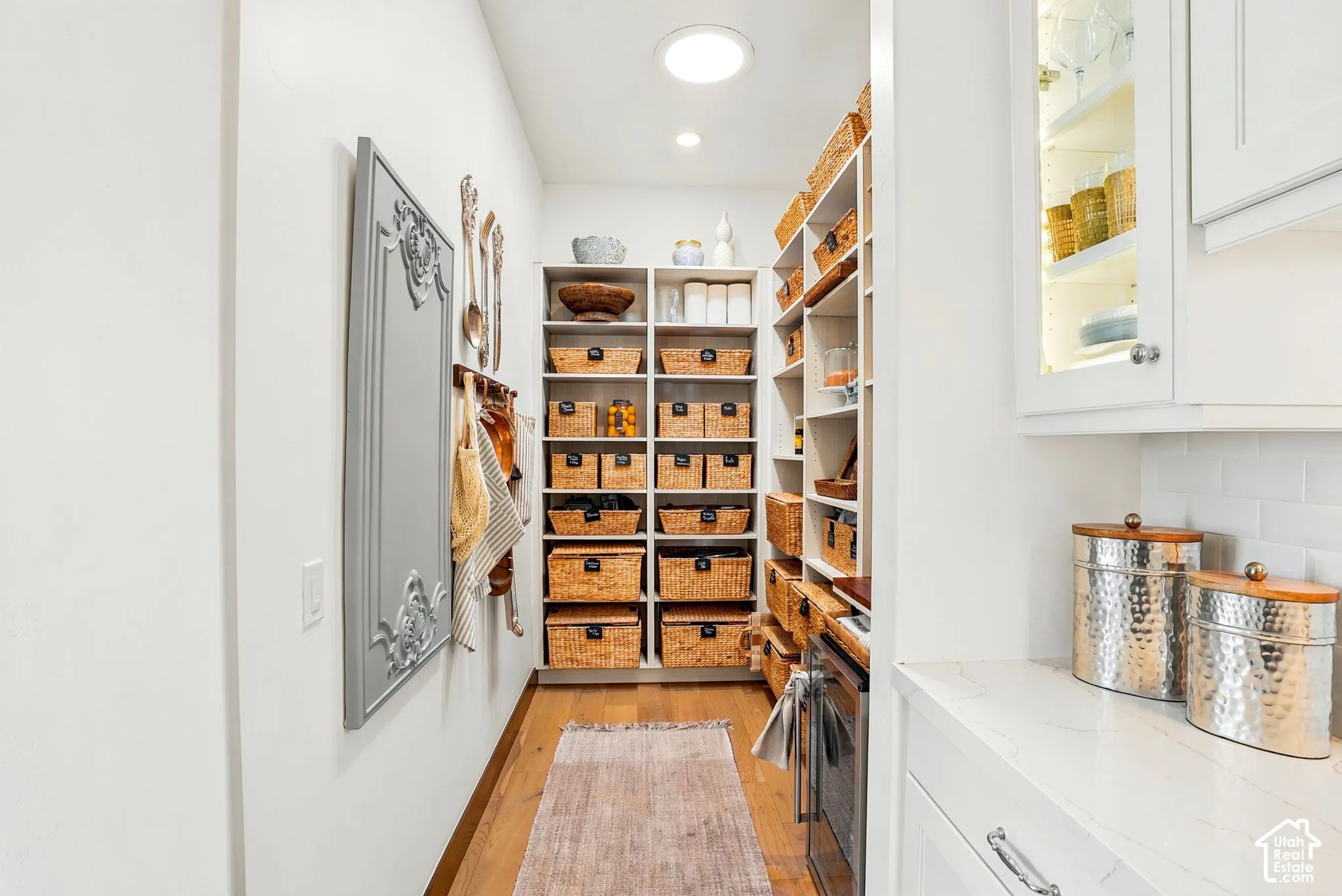 Dedicated pantry space featuring extensive built-in shelving, recessed lighting, and wood-finish flooring