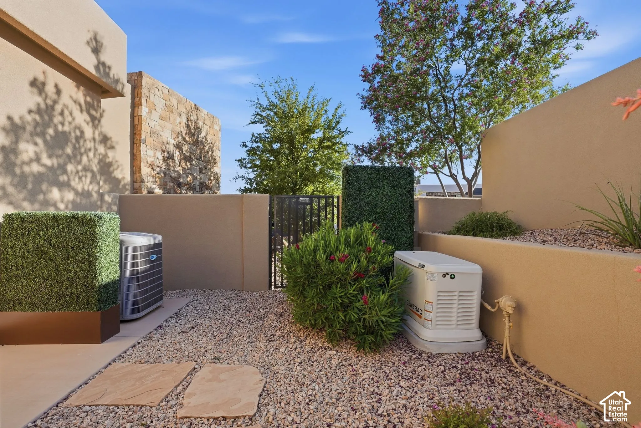 Xeriscape landscaping featuring gravel and mature plantings, complemented by a stone accent wall