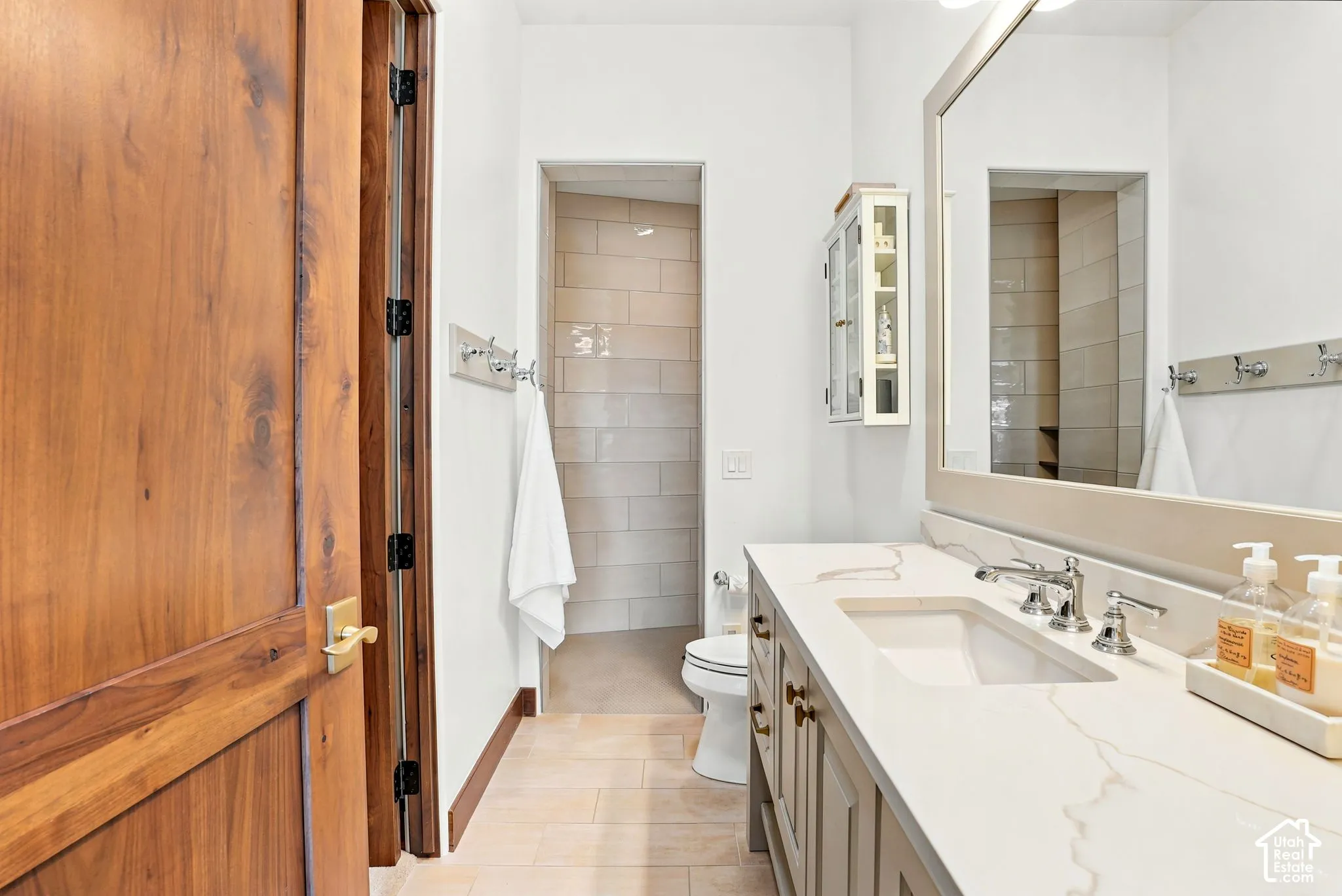 Wood-paneled door, extensive vanity with integrated sink, polished chrome fixtures, framed mirror, and built-in medicine cabinet