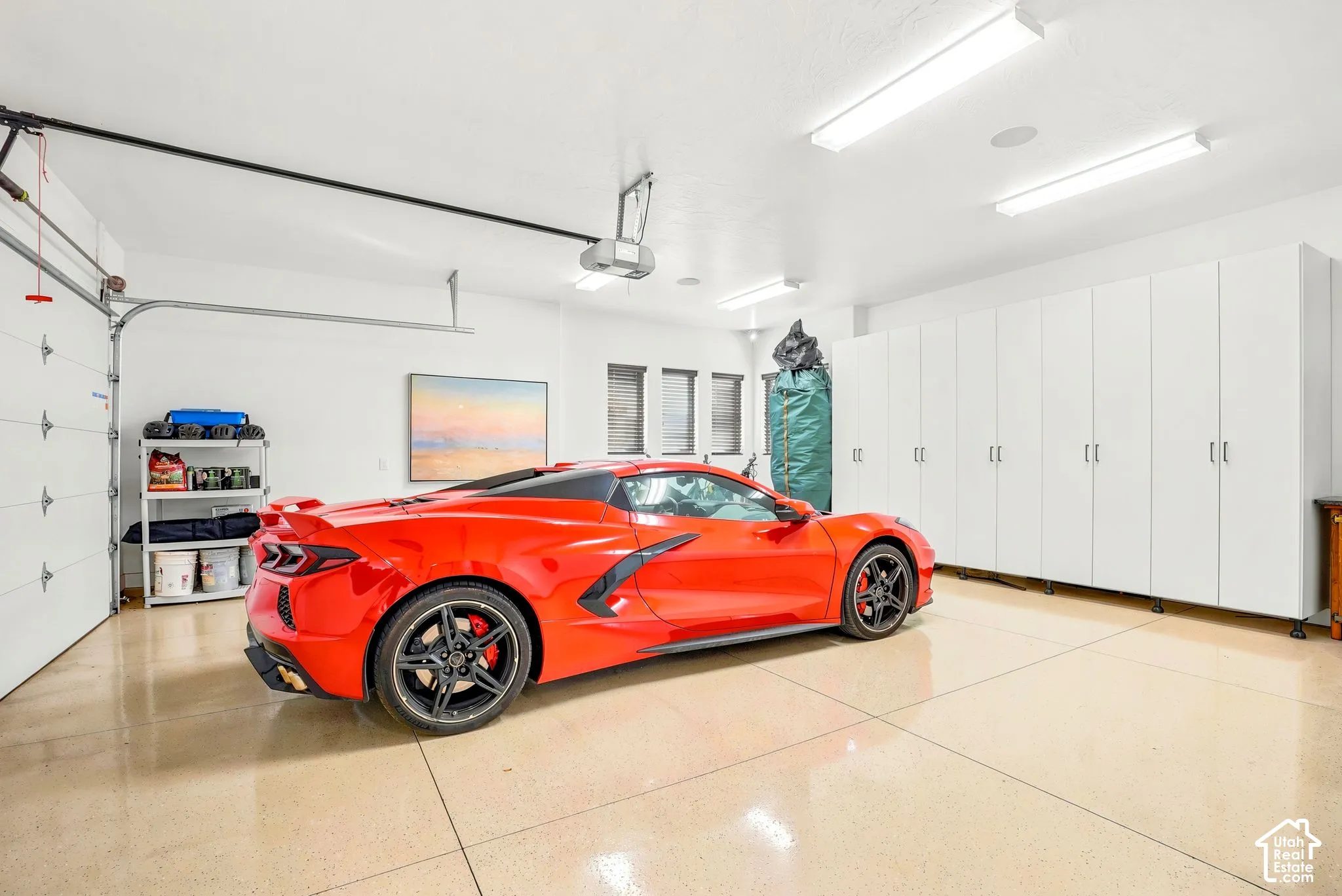 Expansive garage featuring a high-gloss concrete floor, multiple storage cabinets with brushed nickel hardware, and recessed overhead lighting