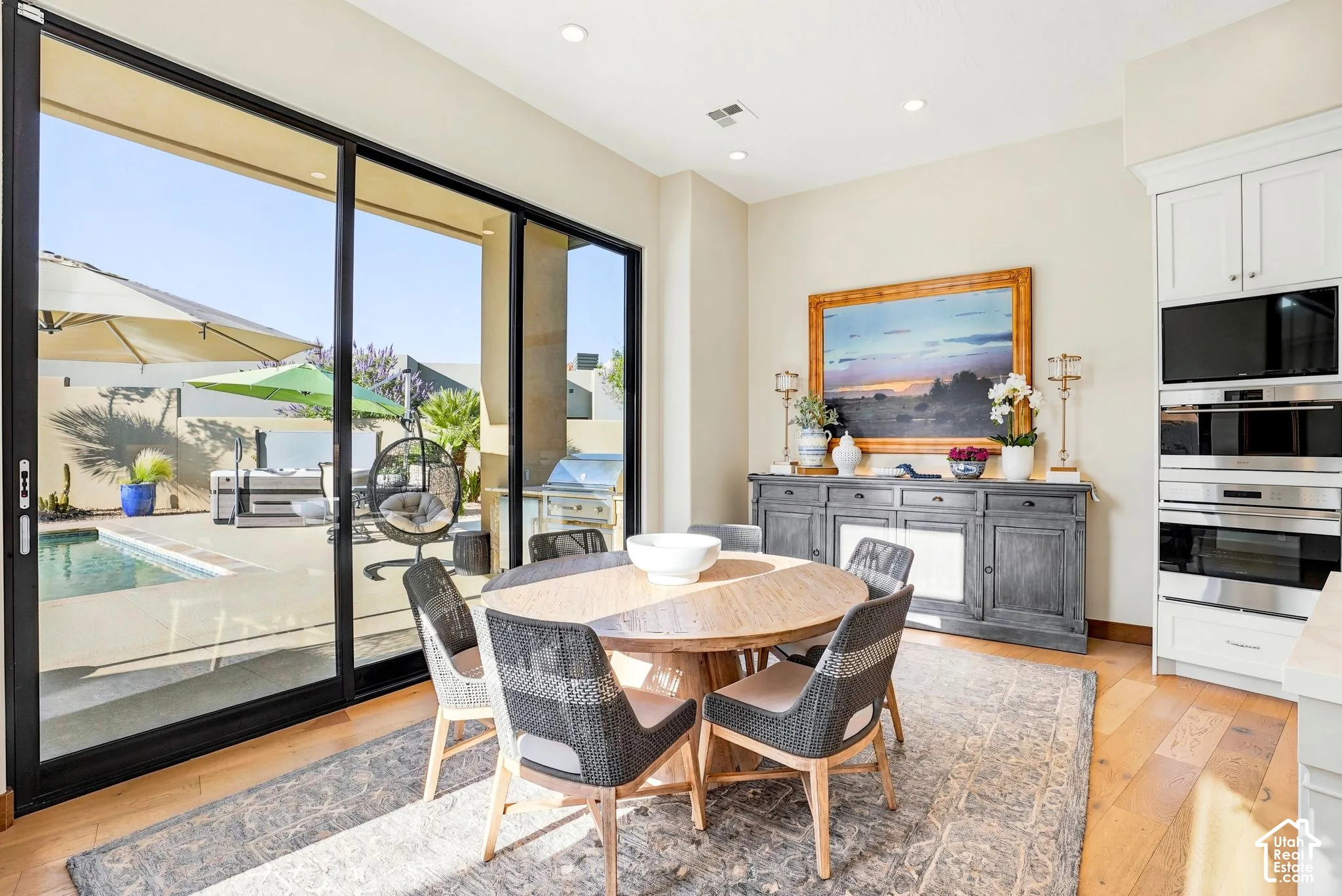 Wood-finish flooring, built-in wall oven with microwave, and sliding glass doors opening to a pool