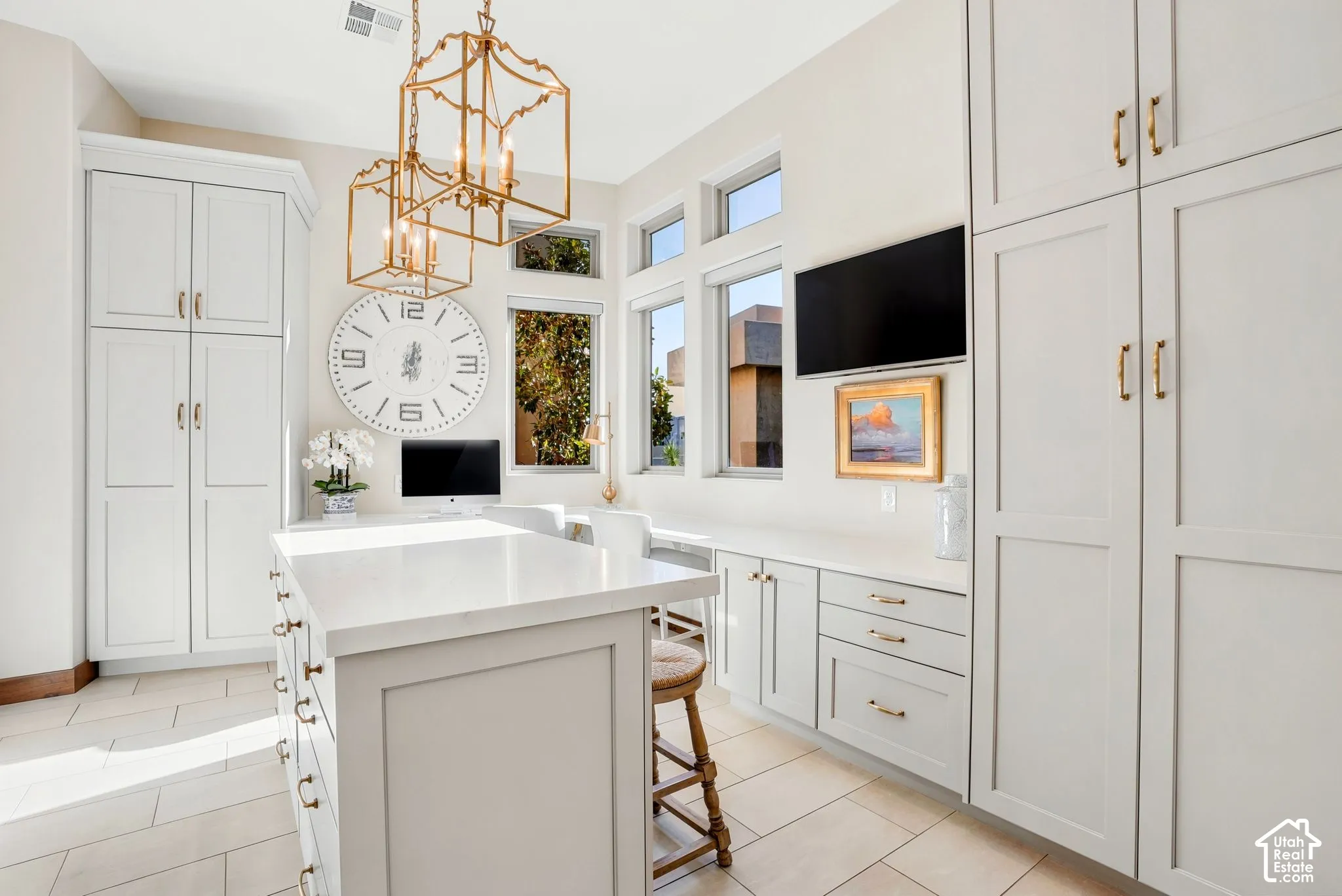 Built-in cabinetry with brass hardware, dual pendant light fixtures, and transom windows