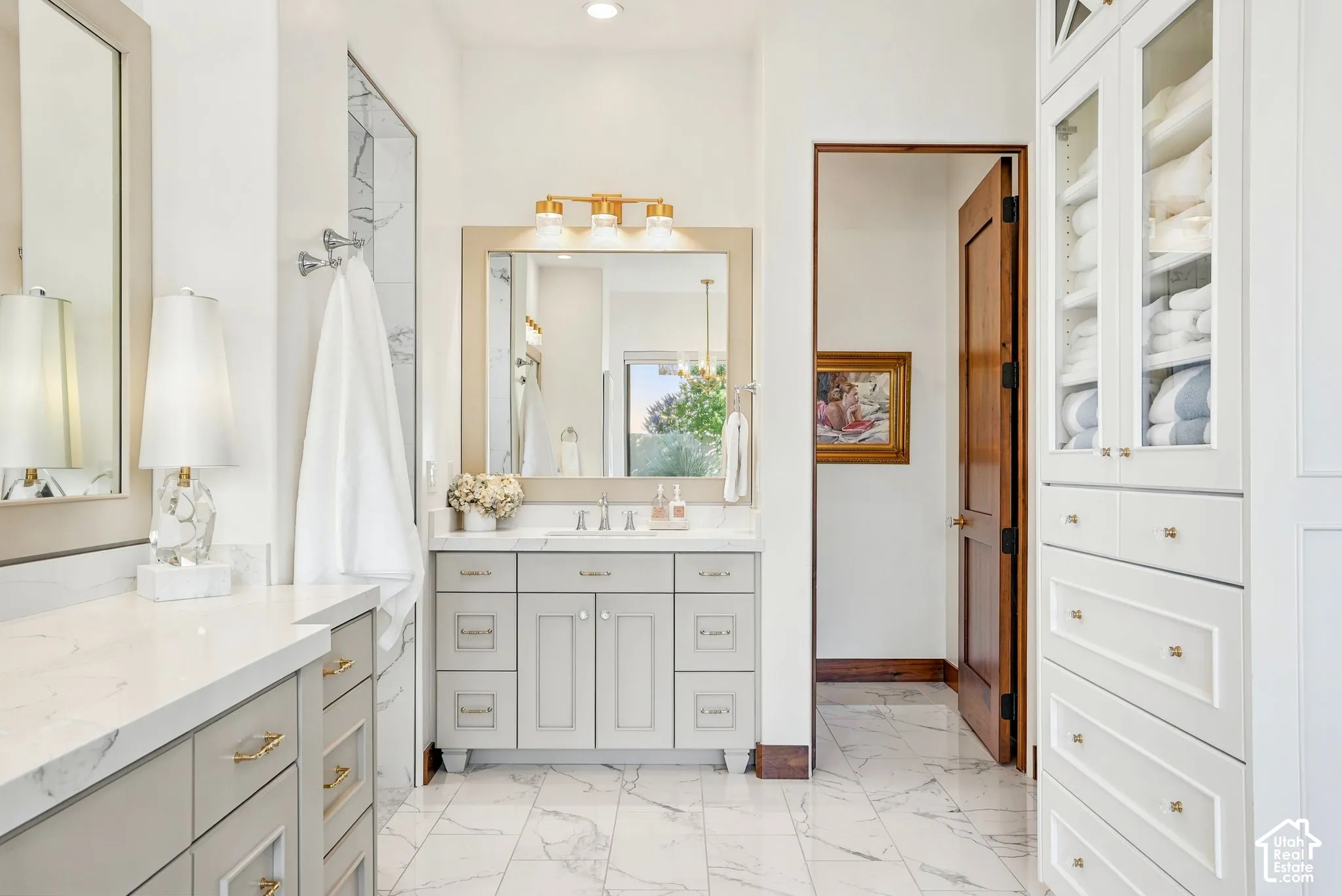 Dual vanity with light gray cabinetry, white countertops, and gold-finish hardware