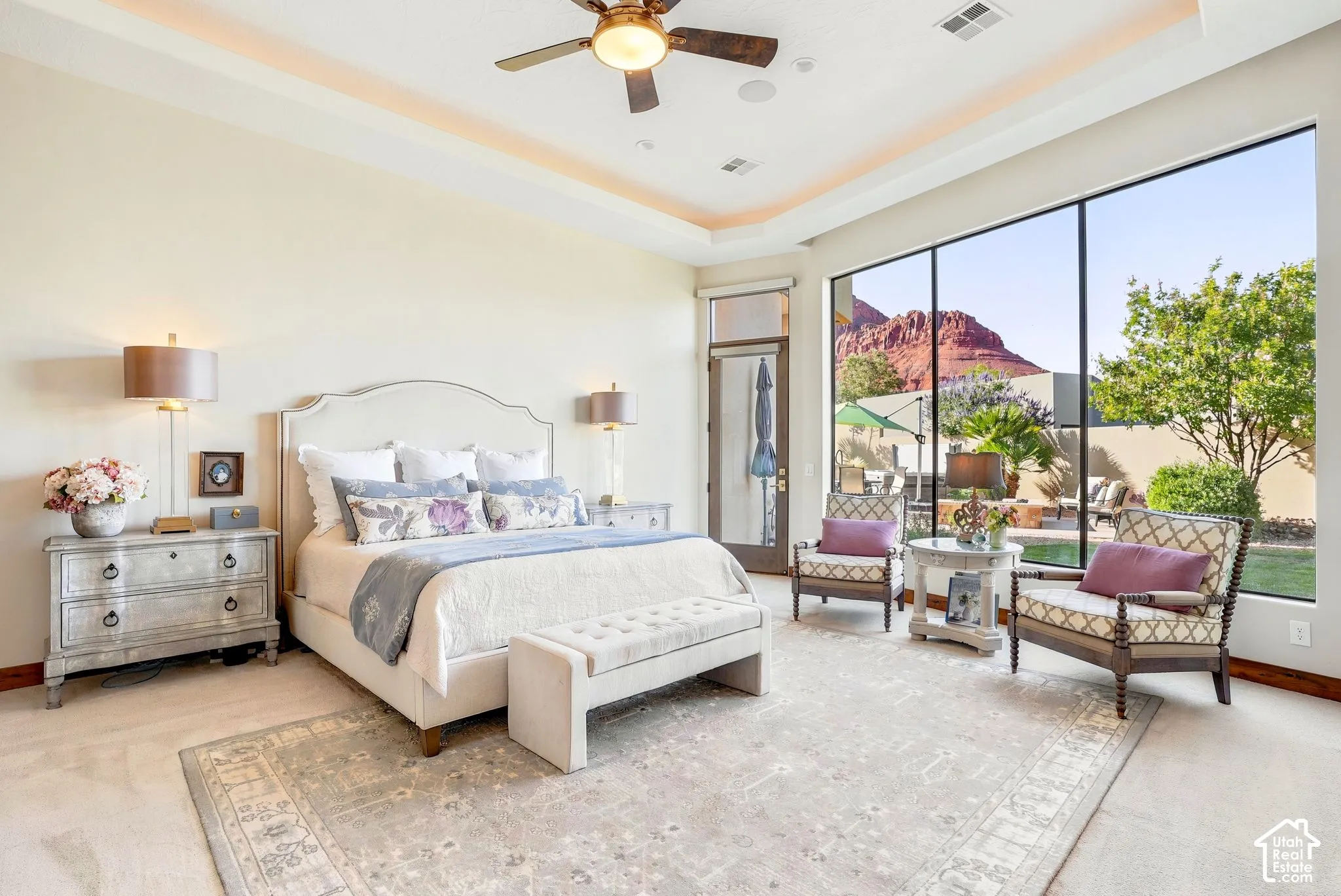 Expansive floor-to-ceiling windows, tray ceiling with recessed lighting, ceiling fan, and direct outdoor access