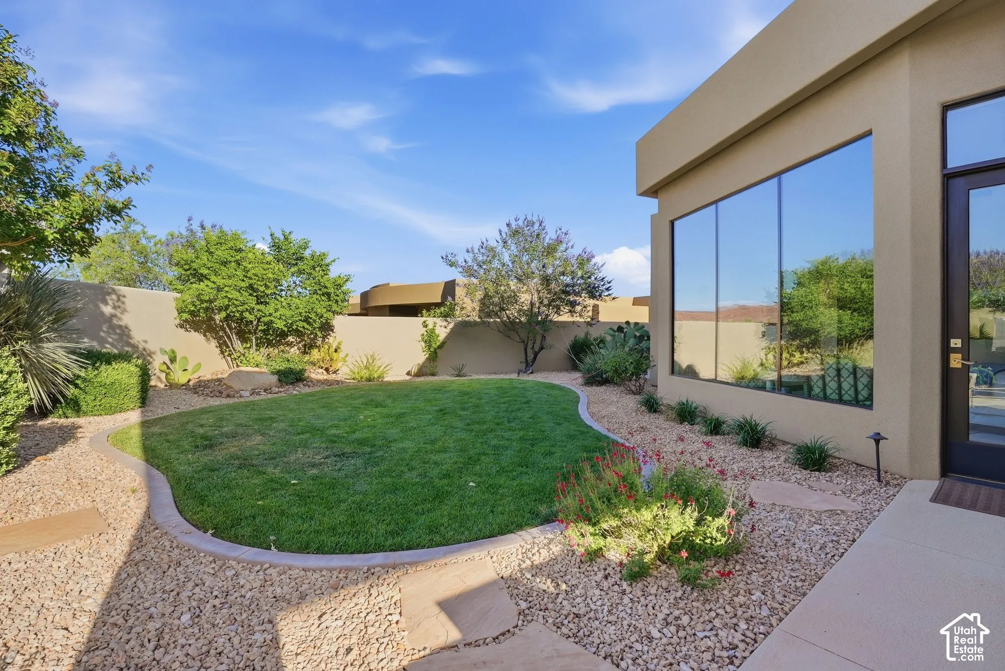 Manicured lawn area with a concrete border, surrounded by decorative gravel and drought-tolerant landscaping