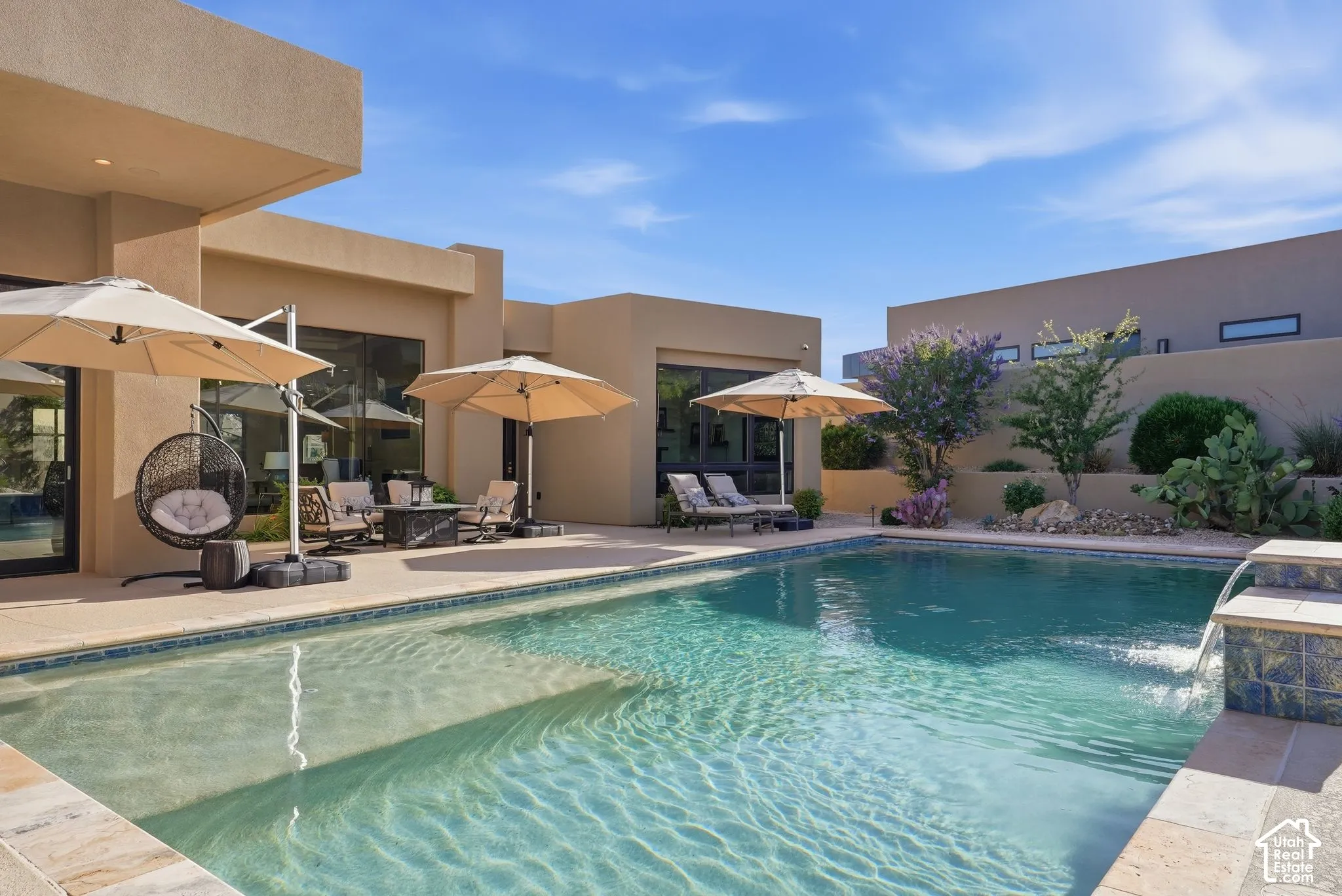 Outdoor pool with a tiled water feature, surrounded by a paved patio and desert landscaping