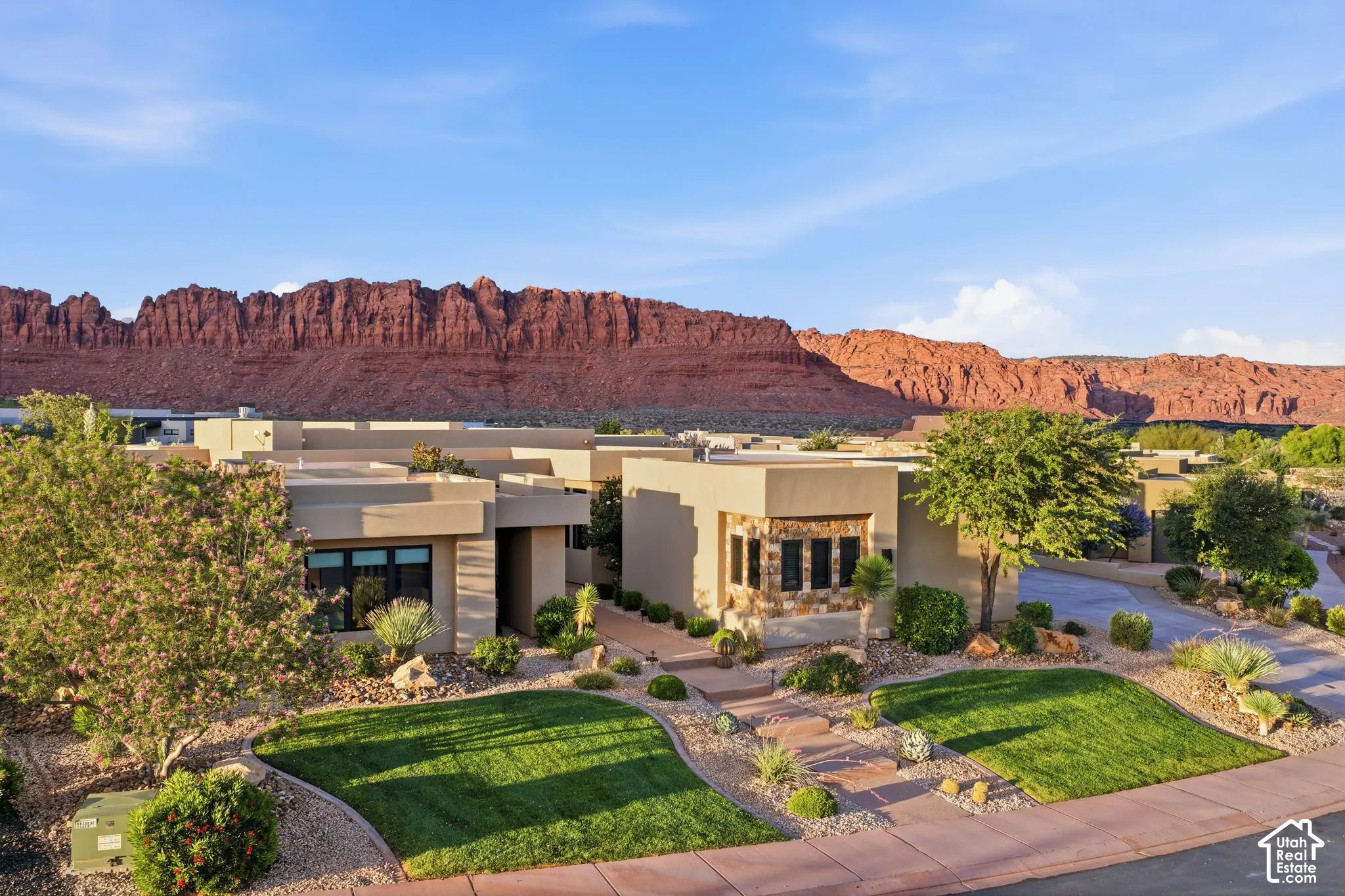 Southwestern architecture with stucco exterior, stone accent wall, and landscaped front yard with green lawn