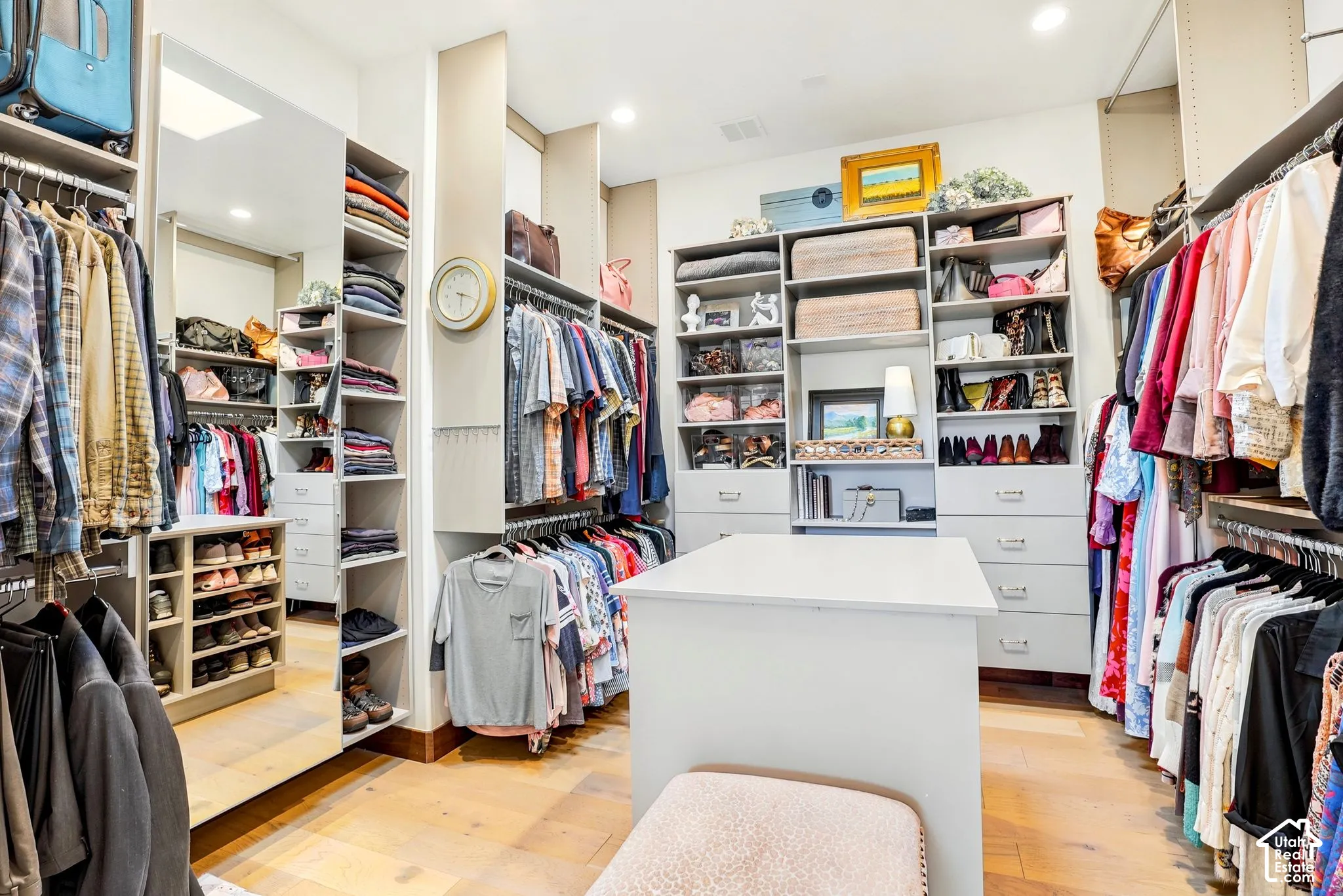 Built-in closet system featuring extensive shelving, hanging rods, storage drawers, and a central island with a solid surface top