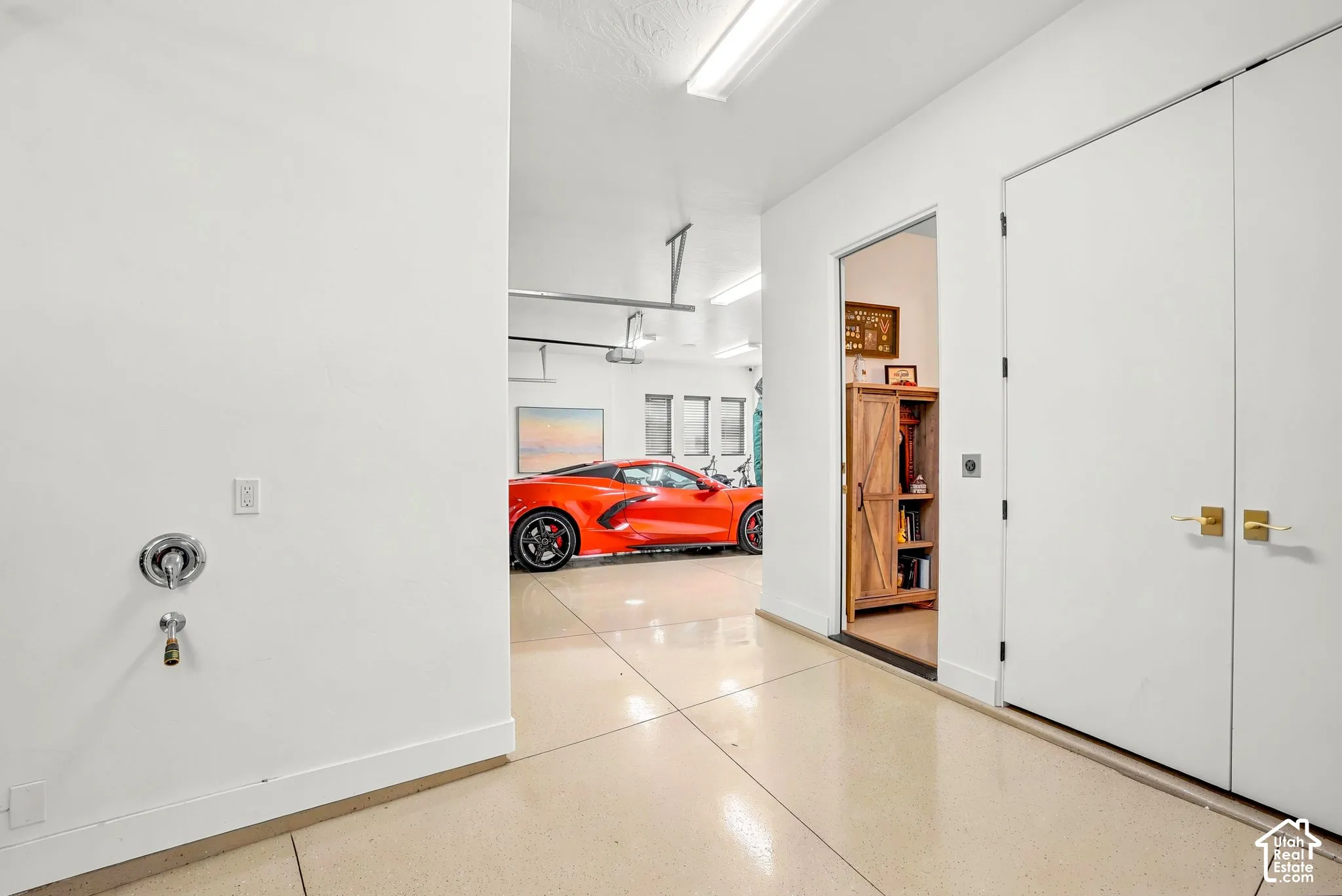 Polished concrete flooring, recessed lighting, double doors with gold-finish hardware, and a utility faucet