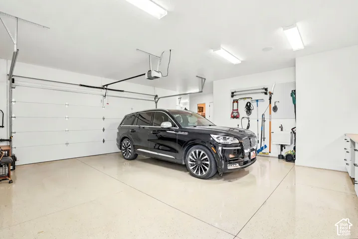 Two-car garage featuring a light-toned epoxy floor finish, overhead lighting, and white walls
