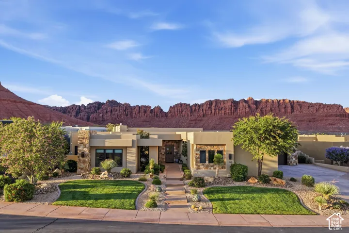 Contemporary stucco exterior with stone accents, mature landscaping, and a manicured lawn