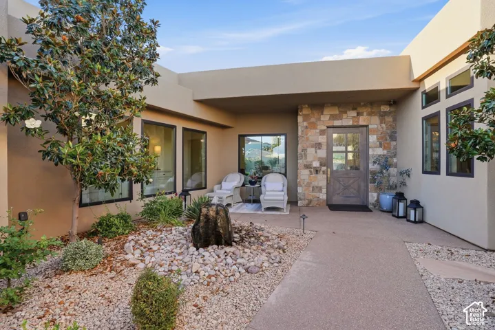 Stucco exterior with stone accent wall, wood-finish entry door, and multi-pane windows